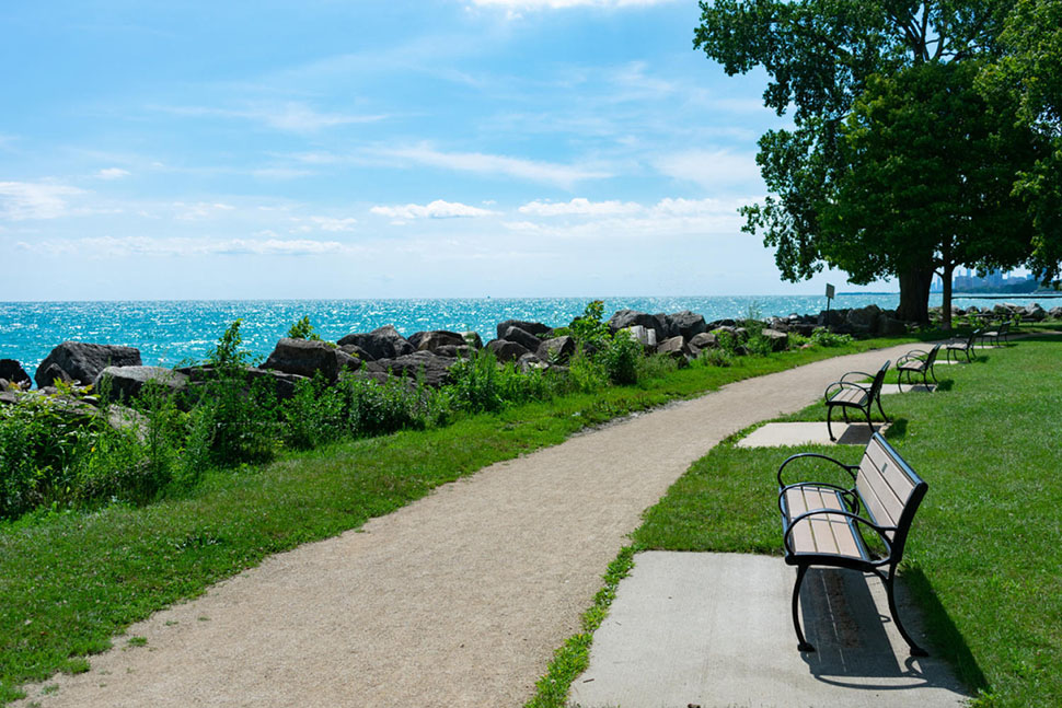 Wooden benches along a walking path in Evanston, IL, offer gorgeous views of Lake Michigan. A large suburb of Chicago, Evanston offers a much more affordable cost of living.