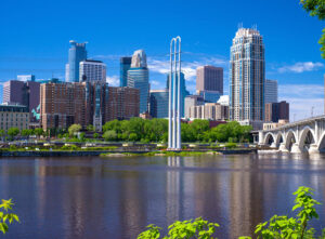 The Mississippi River flows southward by the Minneapolis, MN, skyline. Amenities like a thriving arts and culture scene and cosmopolitan restaurants make Minneapolis one of the best places to live in the U.S.