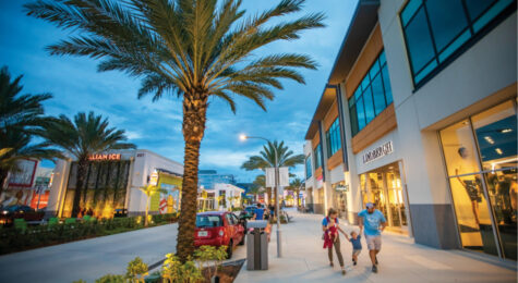 Families stroll along the sidewalks past the storefronts at One Daytona in Daytona Beach, Florida.