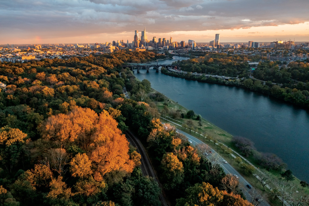 The setting sun highlights the fall colors on the trees at Fairmount Park, while the city skyline can be seen in the distance in Philadelphia, PA.