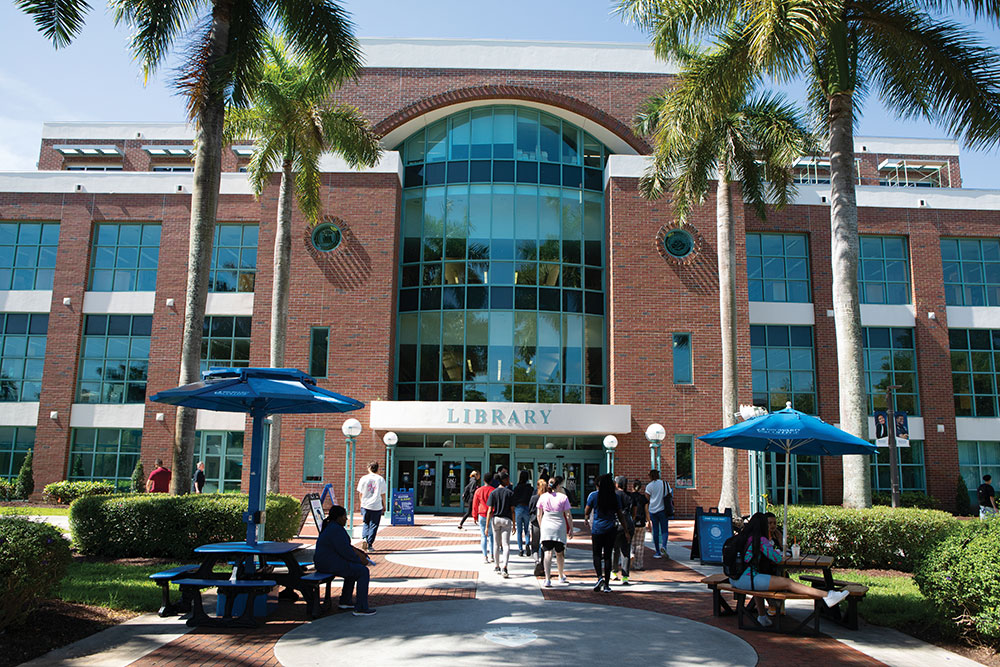 Underneath a canopy of palm trees, students walk to the library at Broward College’s central campus in Davie, FL.