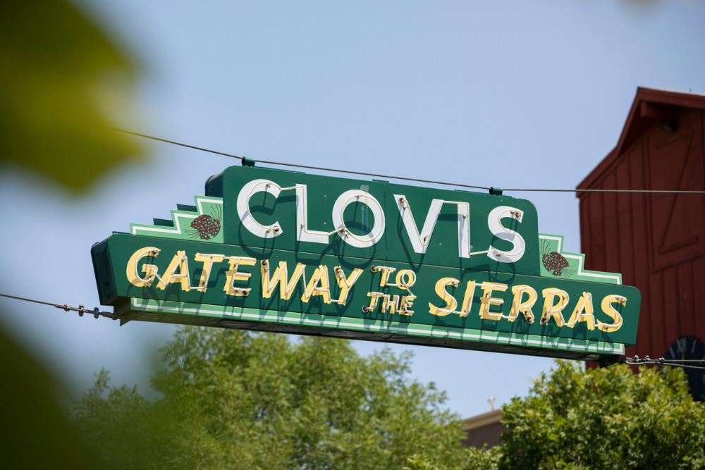 A historic Clovis neon sign hangs over a street in Clovis, California.