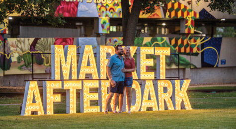 Couple in front of Market After Dark sign