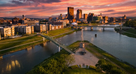 An aerial drone view over a park looking towards downtown Dayton, Ohio at sunset at the confluence of the Great Miami and Mad Rivers.
