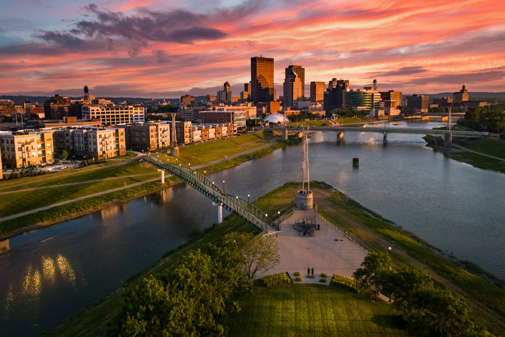 An aerial view of a park located at the confluence of the Great Miami and Mad Rivers, looking toward downtown Dayton, Ohio, at sunset. 