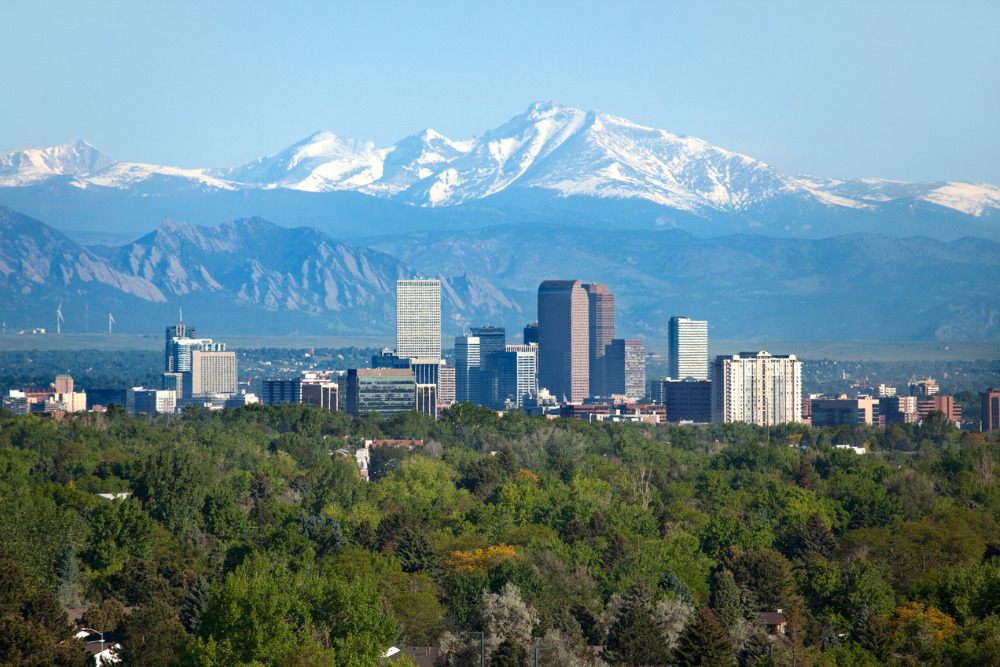 The snow-covered Rocky Mountains stand tall in the background of the Denver, Colorado, skyscrapers.