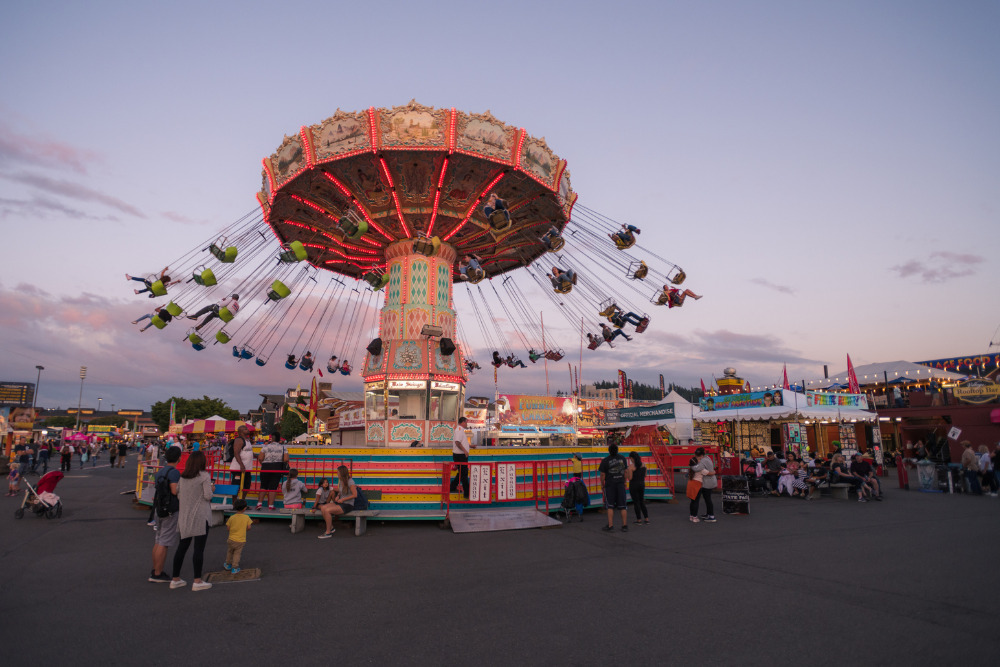 People enjoying the rides at the Washington State Fair at sunset. The Fair is known by locals as the Puyallup fair and has been running since 1900.