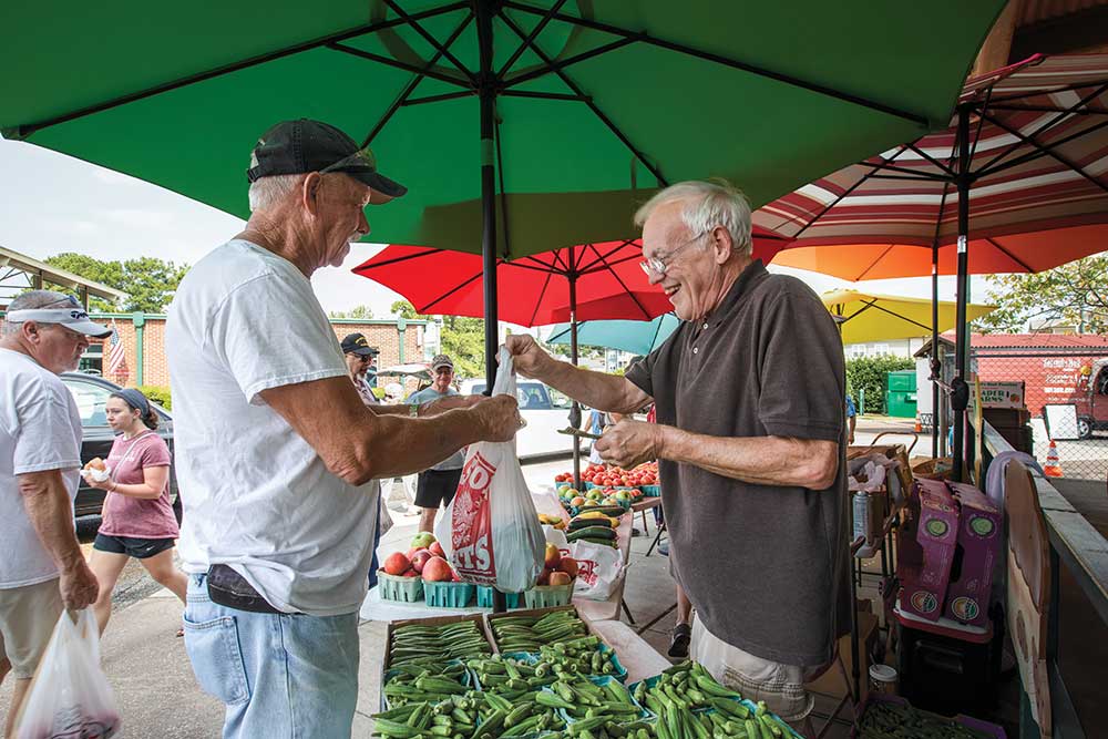 Jack Ellis, left, buys produce from Tommy Hardister at the Bennett-Knott Farm boot at the West Tennessee Farmers Market in the Jackson Walk are near downtown Jackson.