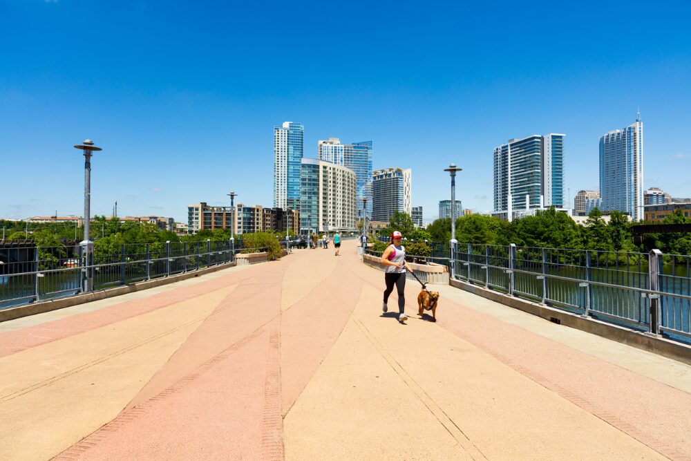 A woman jogs with her dog along a bridge in Austin, Texas, a pet-friendly city.