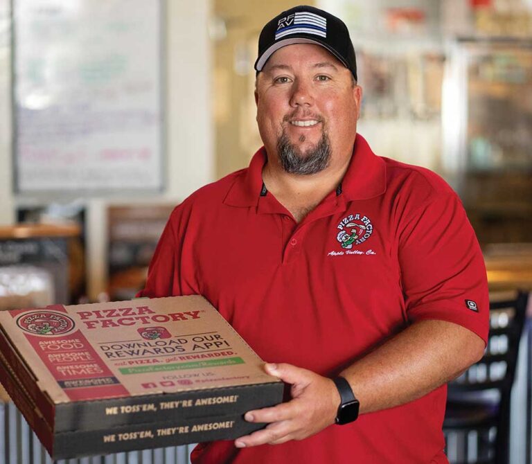CJ Eversole, owner of Pizza Factory, poses with a pizza box.