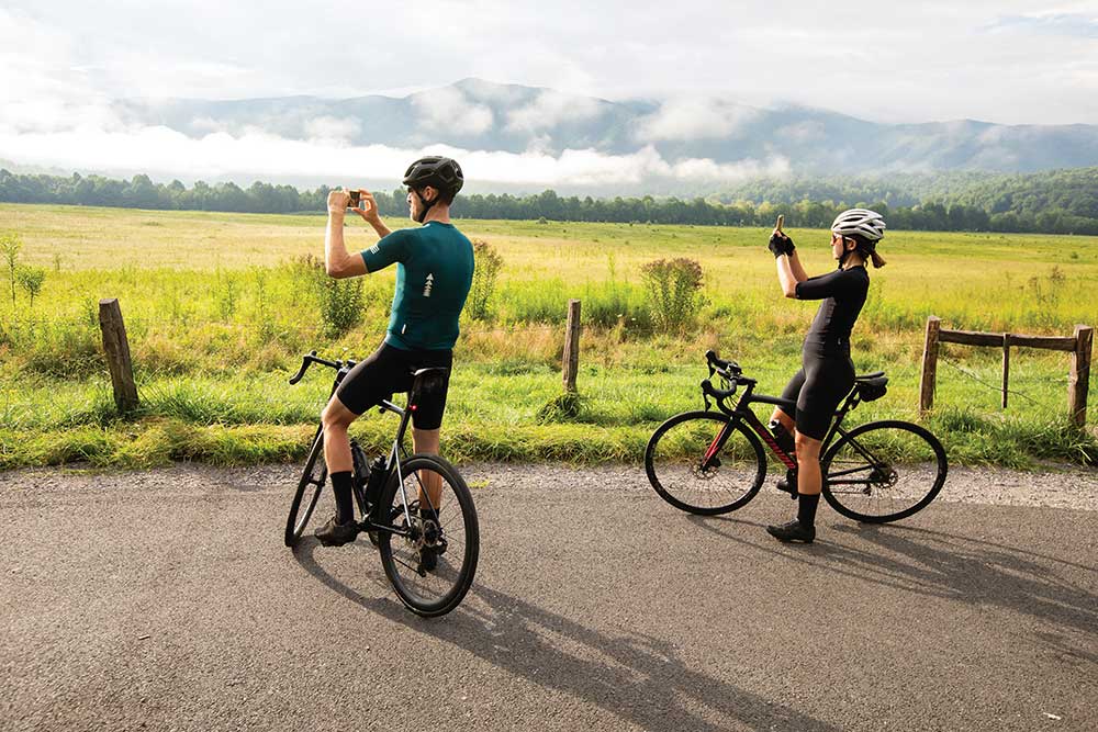 Cyclists photograph the view at Cades Cove during Vehicle-Free Day in Great Smoky Mountains National Park in Townsend, Tennessee, August 2022.