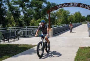 Man rides a bike with a dog in his backpack along the Marion Dual Bridge, which is located along the Grant Wood Trail in the Cedar Rapids, IA, area.