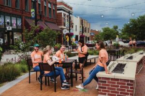 A group of people enjoy beverages and refreshments at one of the outdoor seating areas along Main Street in Marion, IA.