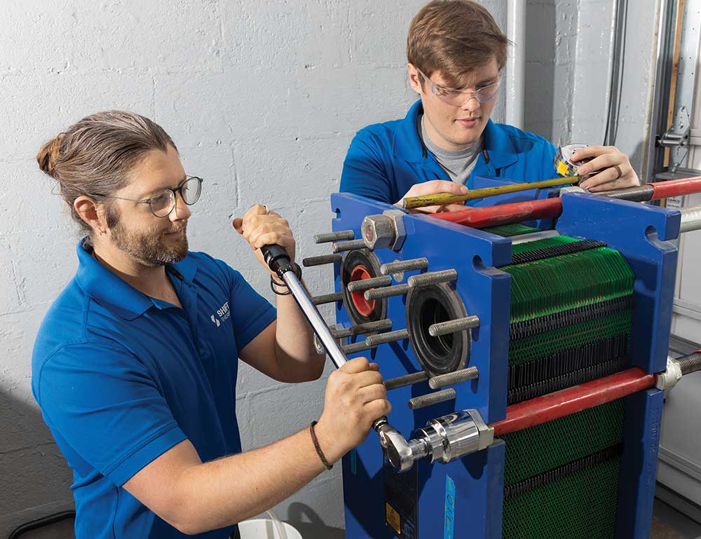 John Cadotte, left, and Jesse Buckley of Shift Thermal assemble a plate-and-frame heat exchanger as part of a New York State Energy Research and Development Authority project, which will be demonstrated in New York in 2025. Shift Thermal was among the first cohort of Innovation Crossroads in 2017. Credit: Genevieve Martin/ORNL, U.S. Dept. of Energy