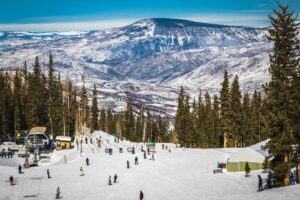 Nice winter day on ski slope in Colorado ski resort near Aspen, Colorado, with skiers and snowboarders going down to chairlift