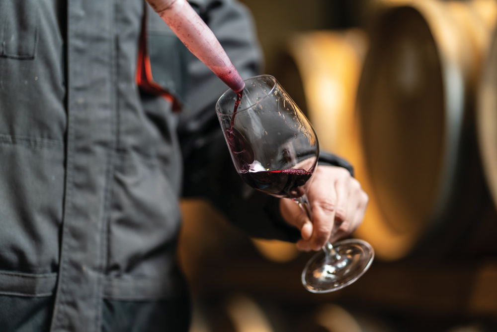 man pouring red wine into glass