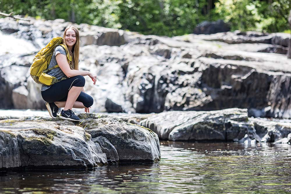 A female hiker stops in front of Breakwater Falls in Florence, WI.