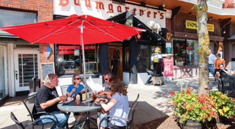 Diners eat lunch at outdoor tables in front of Baumgartner's Cheese Store & Tavern on the Courthouse Square in downtown Monroe, WI.
