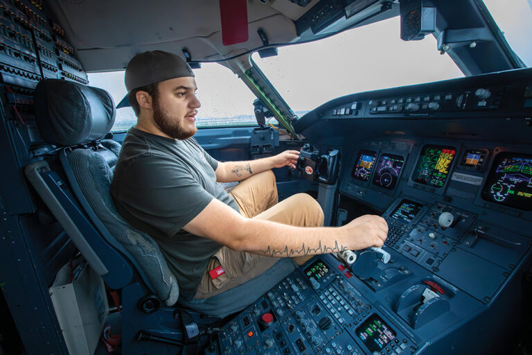A male airframe mechanic student runs through the controls in the cockpit of a Bombardier CRJ200 regional jet while diagnosing an issue with the plane during their studies at Epic Flight Academy’s aircraft maintenance program.