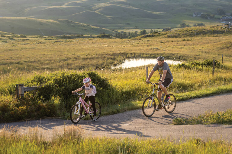 Families ride bicycles on the greenway trail along Casper Mountain Road in Casper, Wyoming. Exploring Casper Mountain is one of many fun things to do in Casper, WY, with kids.