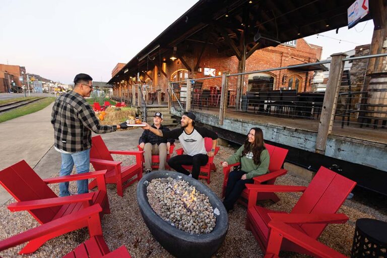 Visitors gather around a fire pit at Gather JC Depot and Burg'r & Barrel in downtown Johnson City, Tennessee.