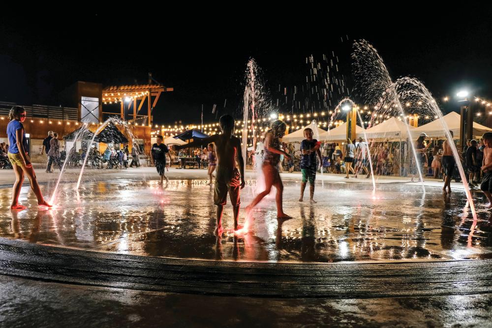 Children play in a water fountain at the 5150 Festival