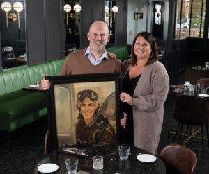 Alex and Stephanie Athan show a portrait of Alex’s grandfather, Augie Athan, in their 1922 on the Square restaurant in Newark.