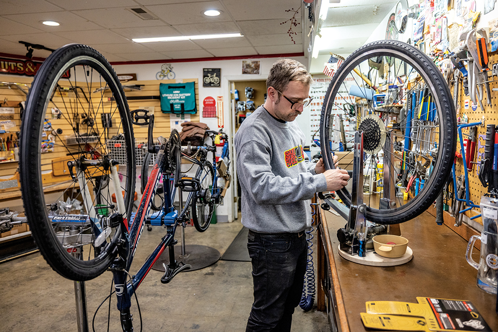 Nash Wiley works on a customer's bicycle in the maintenance shop at Skunk River Cycles in downtown Ames, Iowa.