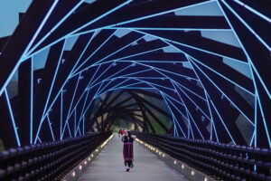 A woman takes a selfie while walking across the High Trestle Trail Bridge in Madrid, Iowa. The bridge lights up in blue at night.