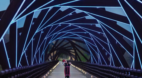 A woman takes a selfie while walking across the High Trestle Trail Bridge in Madrid, Iowa. The bridge lights up in blue at night.