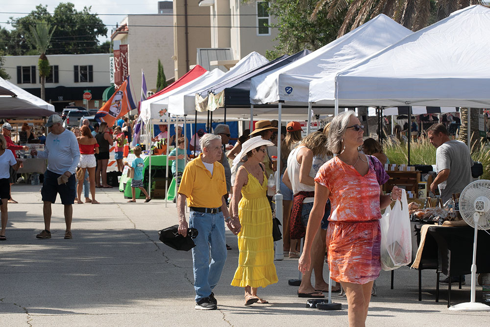 Visitors browse the vendor stalls at the New Smyrna Beach Farmers Market in New Smyrna Beach, FL.