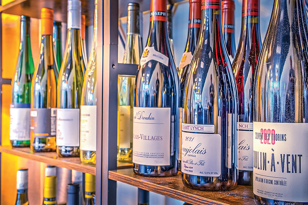 Wine bottles glint on shelves at Beaker & Flask in Gainesville, FL.