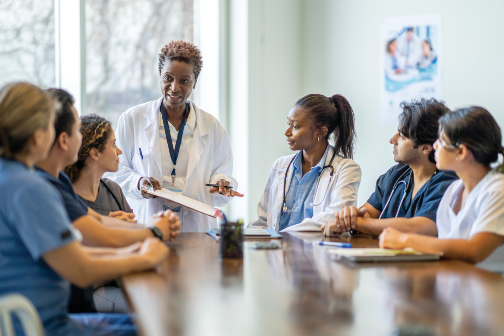 A group of diverse nursing students sit around a boardroom table