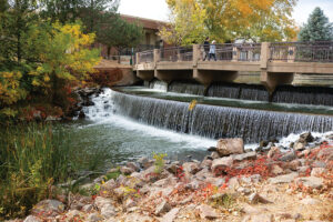Visitors walk across a waterfall along the Historic Arkansas Riverwalk in downtown Pueblo, CO.