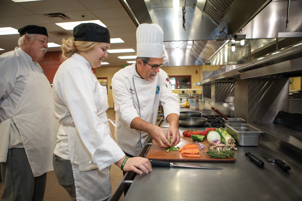 Chef instructor Mark McCann, right, instructs Terry Grubbs, left, and Abigail Killian in the kitchen at the Mori Hosseini College of Hospitality and Culinary Management on the Daytona State College campus.