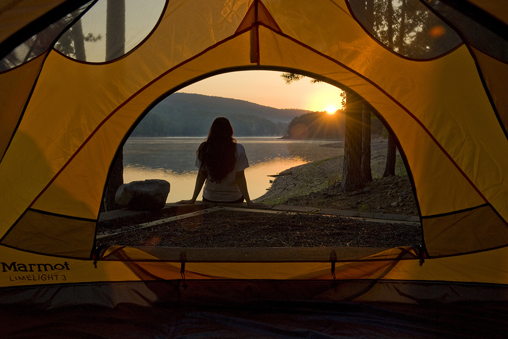 A woman looks out over Ouachita Lake from her tent on the shore at Ouachita State Park in Arkansas.