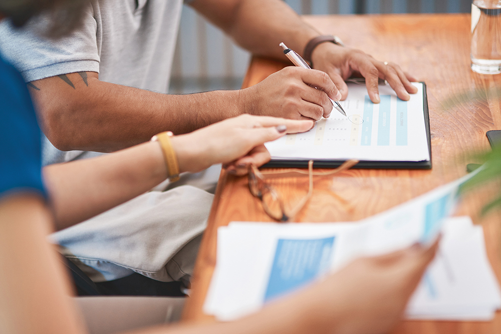 Closeup of a man and a woman's hands as they look at insurance documents.