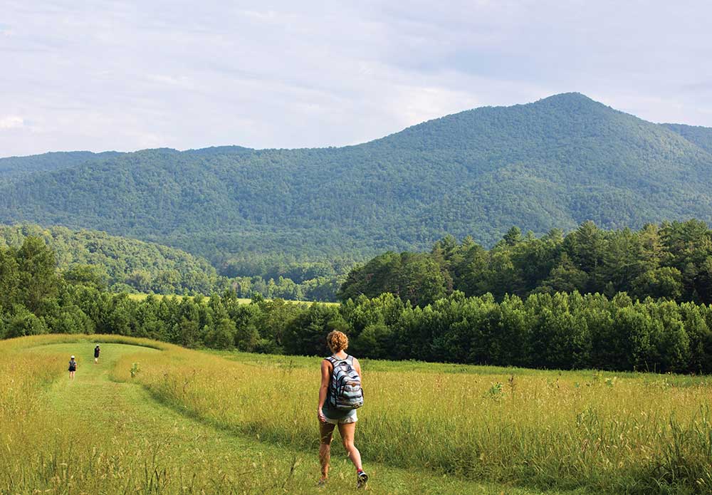 Visitors hike through a field at Cades Cove during Vehicle-Free Day in Great Smoky Mountains National Park in Townsend, Tennessee.