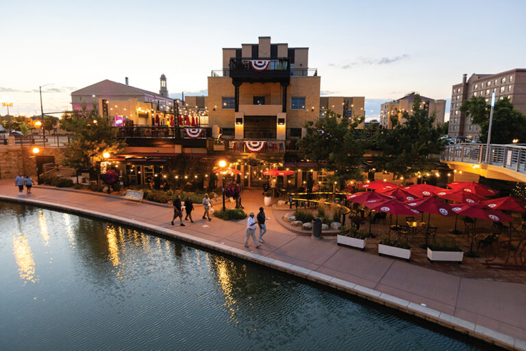 Colorful red umbrellas cover outdoor seating at Brues Alehouse Brewing Co. along the Historic Arkansas Riverwalk in downtown Pueblo, CO.
