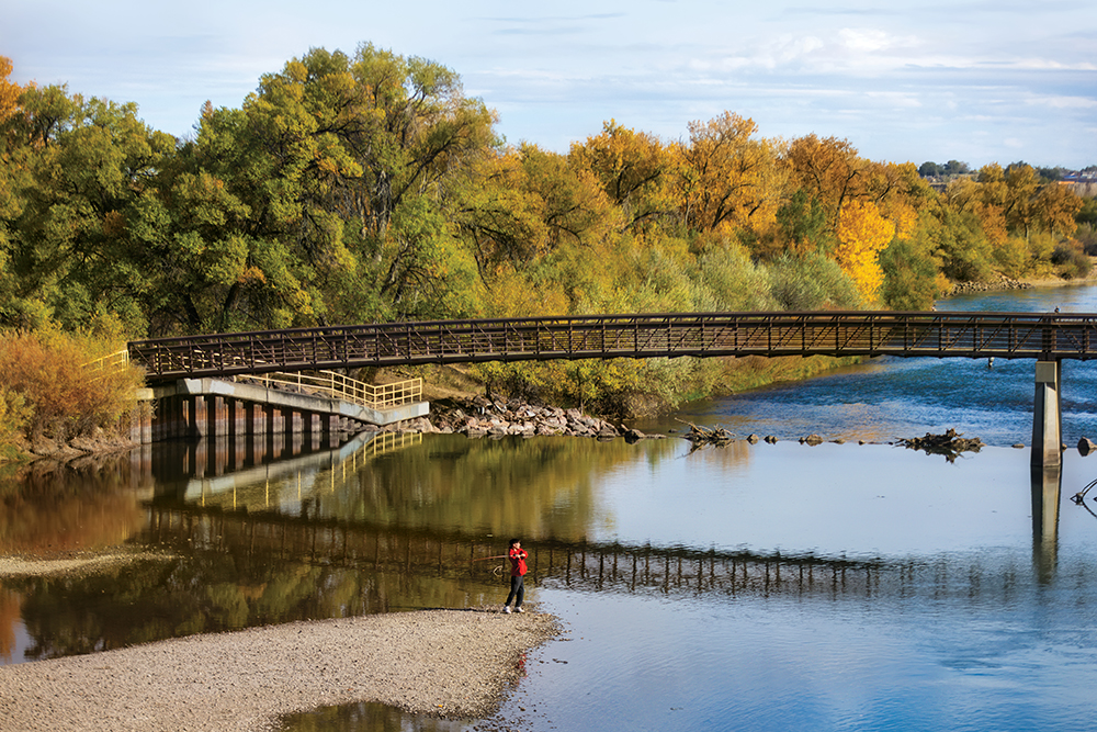 A man fishes from the shore along the Arkansas River in Pueblo, CO.