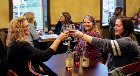Three women make a toast while enjoying wine at Olde Schoolhouse Vineyard & Winery.