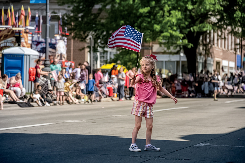 A little girl waves an American flag as a parade approaches for Celebrate CB in Council Bluffs, Ia.