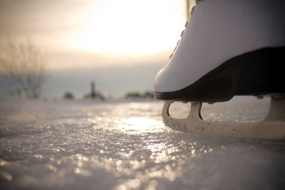 Ice skating. Ice skates in action closeup outdoors. Classic figure ice skates on frozen lake outdoors in evening light.