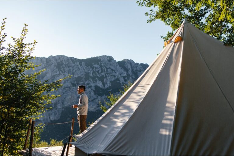 Man Enjoying Morning Coffee Next to Mountain Tent stock photo