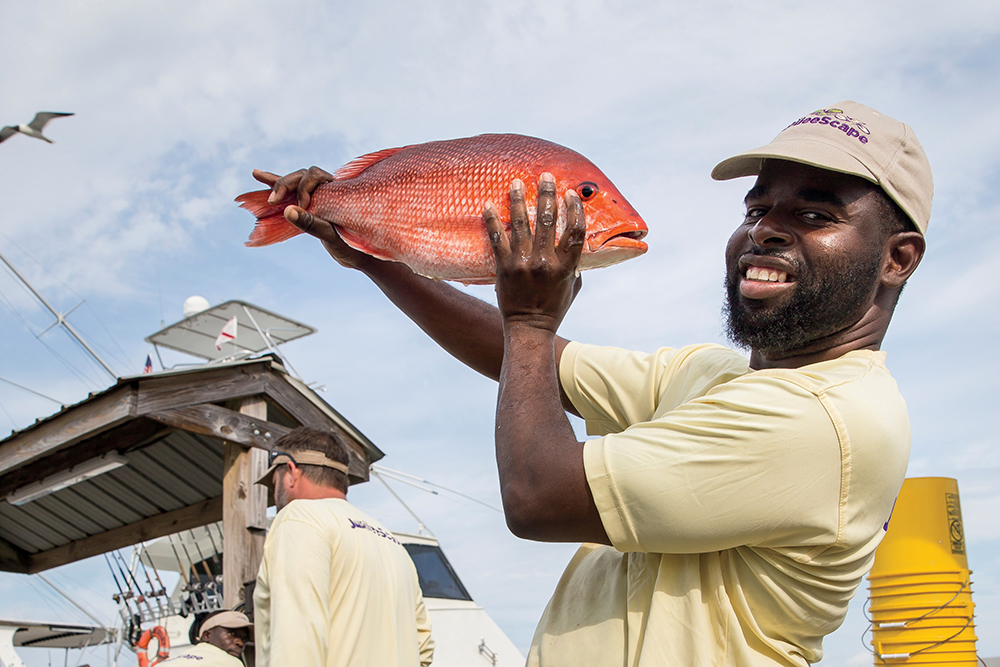 A man poses with a fish on Dauphin Island in Alabama. Fishing is one of the top outdoor activities in Mobile, AL.