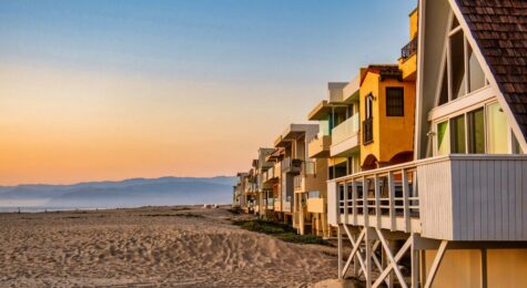 Oxnard, United States - February 21 2020 : colorful wooden rental properties lined up at the beach with an idyllic sunset