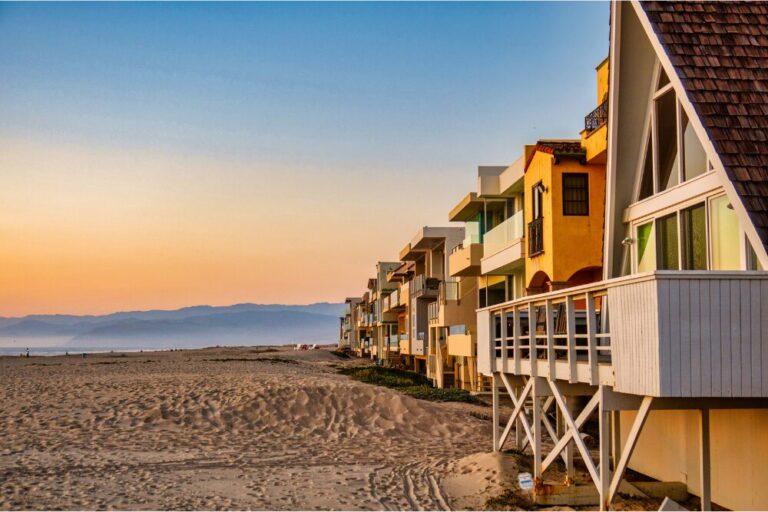Oxnard, United States - February 21 2020 : colorful wooden rental properties lined up at the beach with an idyllic sunset