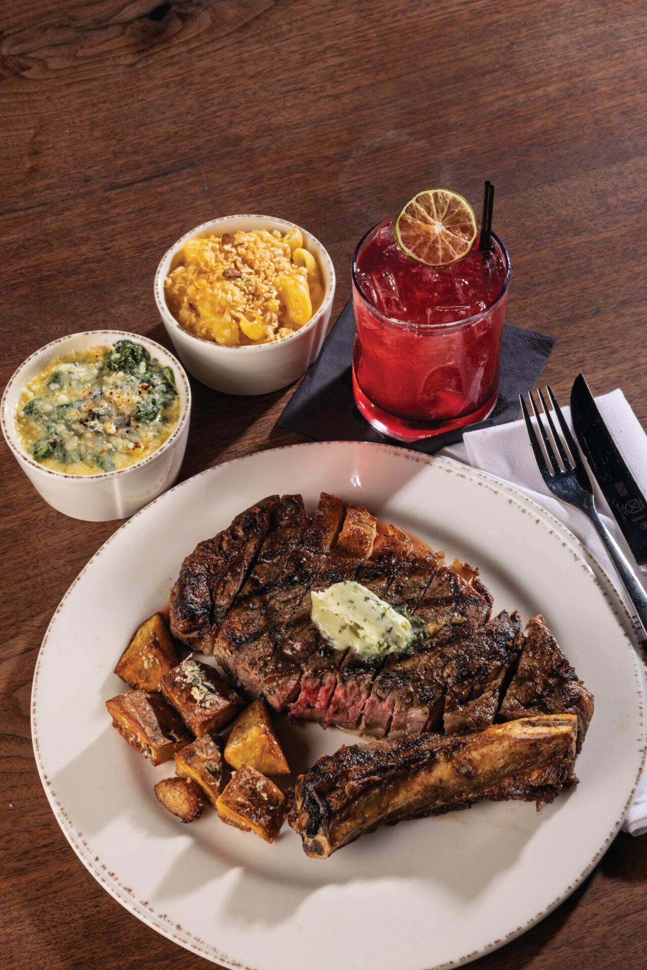 A dry-aged bone-in ribeye locally sourced from Bear Creek Farms with creamed spinach and mac and cheese at Prime & Pint in Columbia, TN.