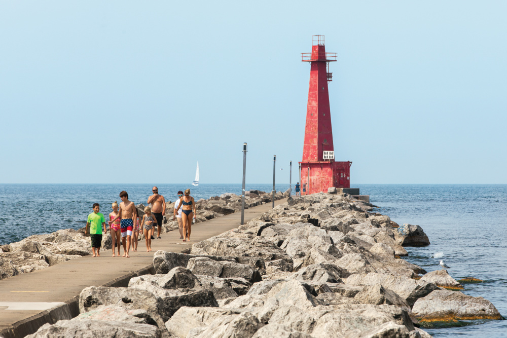 People walk near the south lighthouse near Pere Marquette Park in Muskegon.