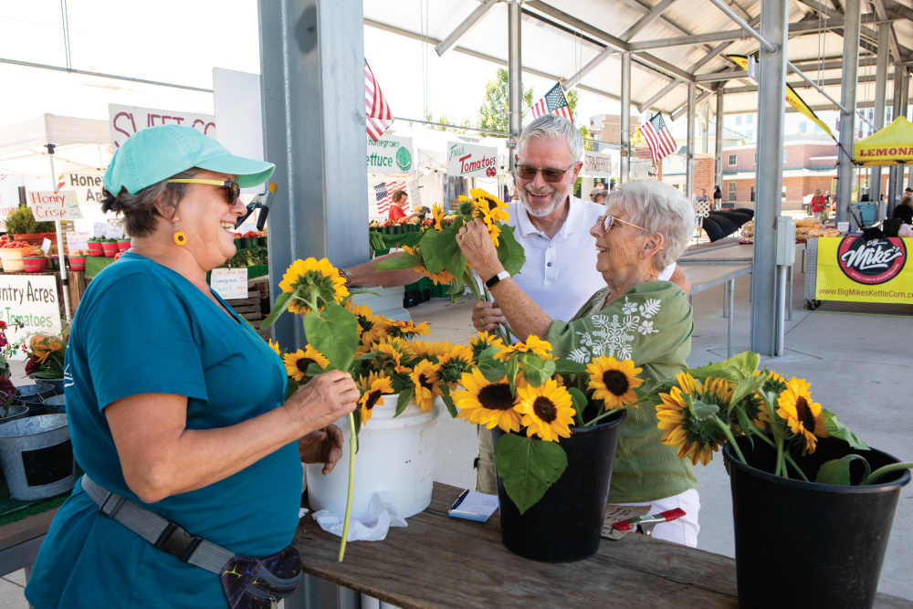 Wilhelmina and Bruce Vanderkooi buy sunflowers from Lisa Chester at The Flower Farm booth at the farmers market in downtown Muskegon. 
